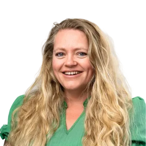 Een vrouw met lang blond haar en een groene blouse lacht naar de camera.