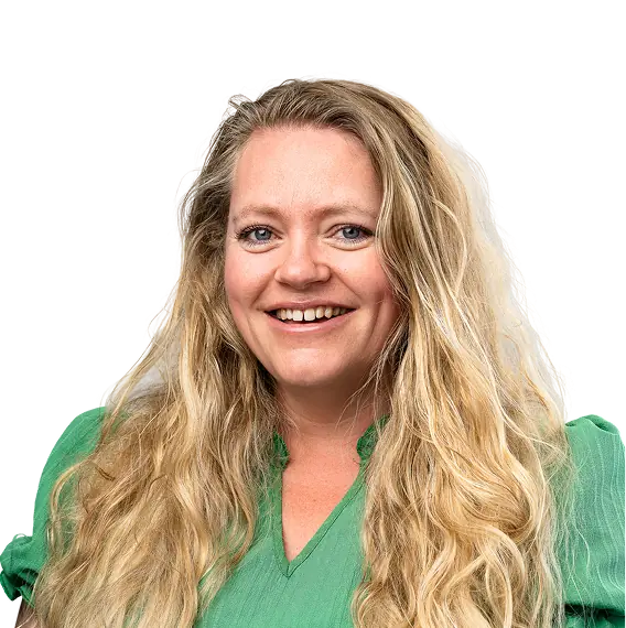Een vrouw met lang blond haar en een groene blouse lacht naar de camera.