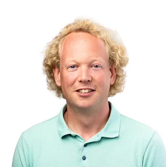 Portret van een lachende man met blond krullend haar in een lichtblauwe polo.