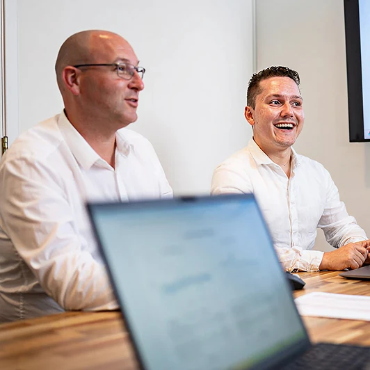 Twee mannen in witte overhemden geven energieadvies tijdens een vergadering bij Energy Check.