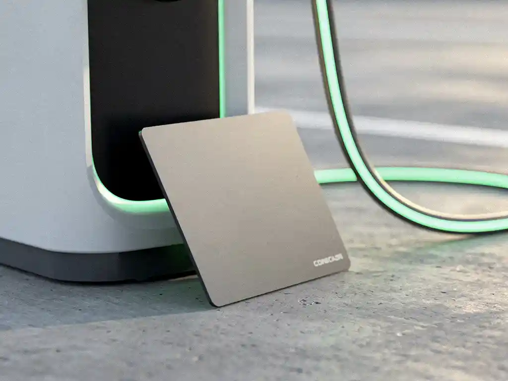 Elektrische laadpas leunend tegen een moderne EV-laadpaal met oplichtende kabel, gefotografeerd op ooghoogte in daglicht.